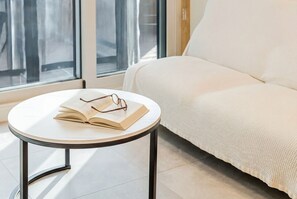 A round table with a book and glasses, a white sofa, and a window with curtains. - Gyeongju Sanmaru Pension (Gyeongju)