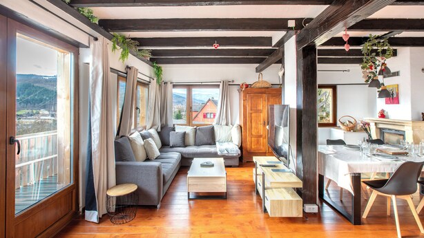 Un salon moderne comprenant un canapé, une table basse et un coin repas avec des chaises.