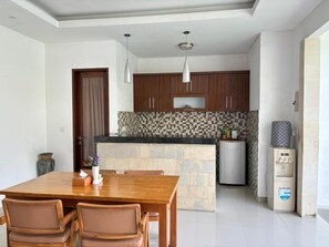 A modern kitchen with wooden cabinets, a central island, and a built-in refrigerator. - Kubu Manggala 1-Bedroom Private Pool Villa Include Breakfast (Kerobokan Kelod, Badung)