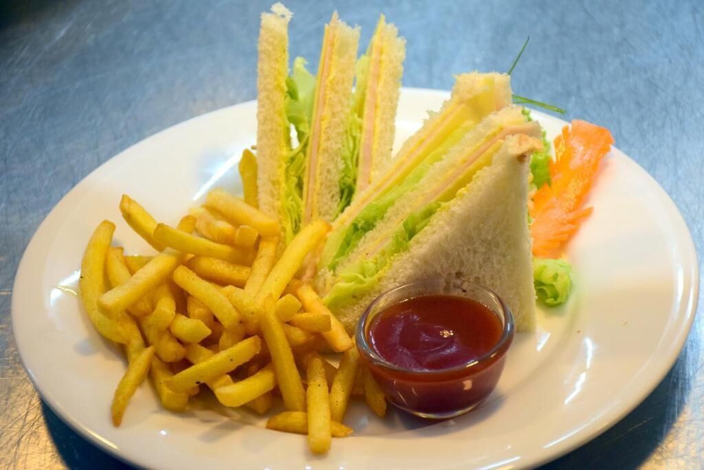 A plate with a sandwich, fries, and a small bowl of ketchup.