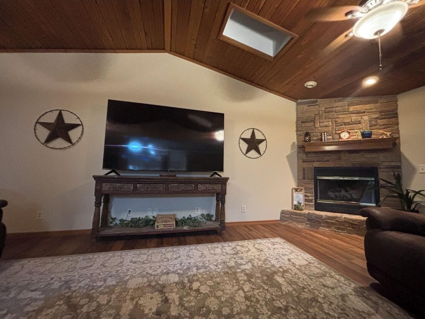Una sala de estar con una televisión de pantalla plana montada en la pared, una chimenea y dos adornos con forma de estrella.