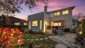Une maison moderne à deux étages dotée d’un patio, d’un espace salon extérieur et d’une entrée bien éclairée.