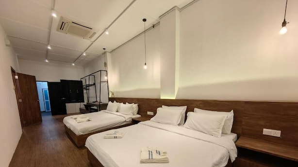 A hotel room with two beds, wooden headboards, white linens, and a wooden floor. - Kangsar Inn 73 (George Town)