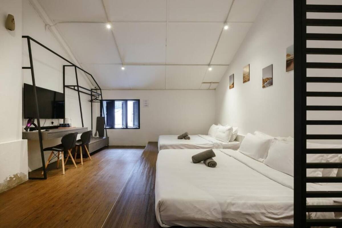 Une chambre moderne avec deux lits, un bureau et une télévision.