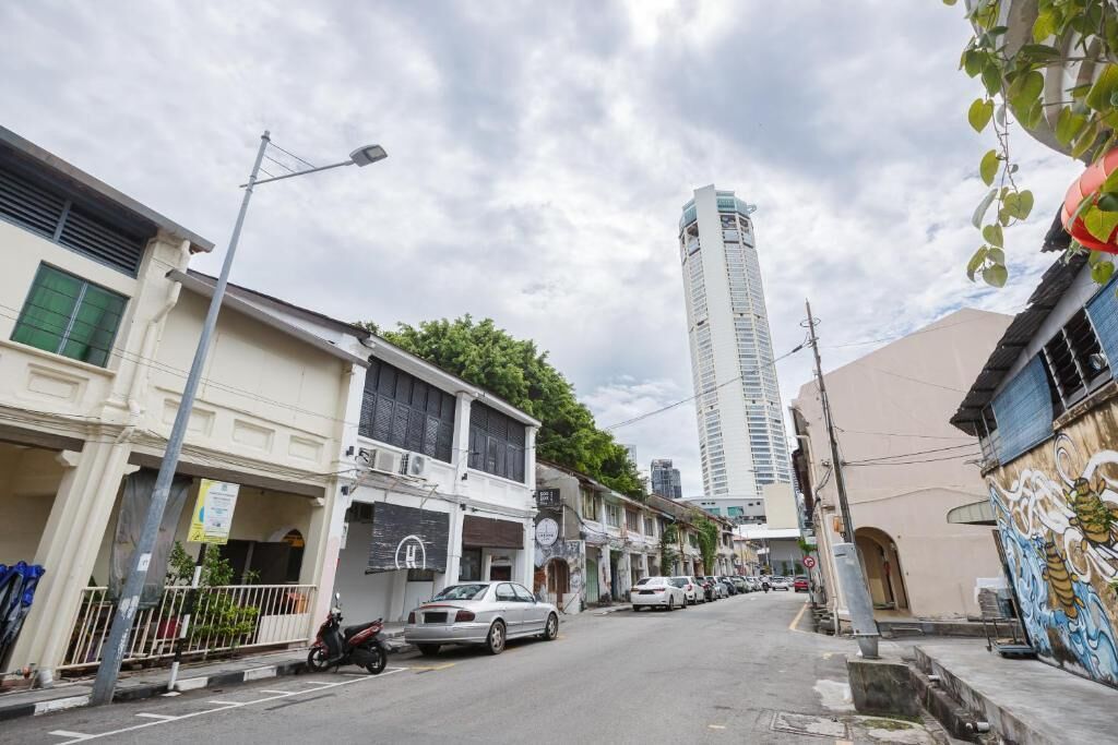 A street view with buildings, parked cars, and a tall skyscraper in the background.