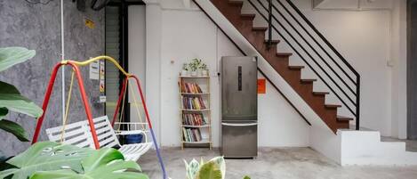 A modern interior with a staircase, a swing set, and a bookshelf.