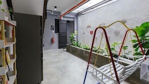 A hallway with a concrete floor, a fire extinguisher, a door labeled '5', and a hanging chair. - Kangsar Inn 73 (George Town)