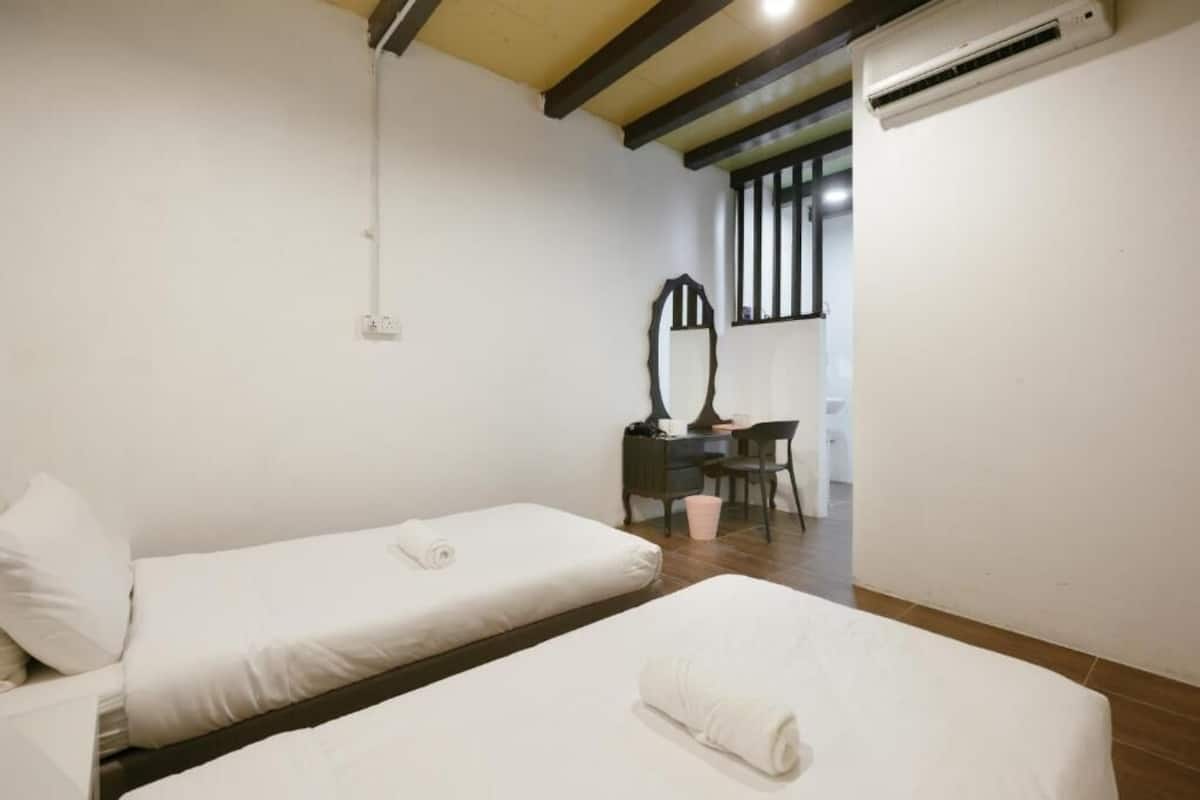 Une chambre avec deux lits simples, un bureau avec une chaise, un miroir et un appareil de climatisation.