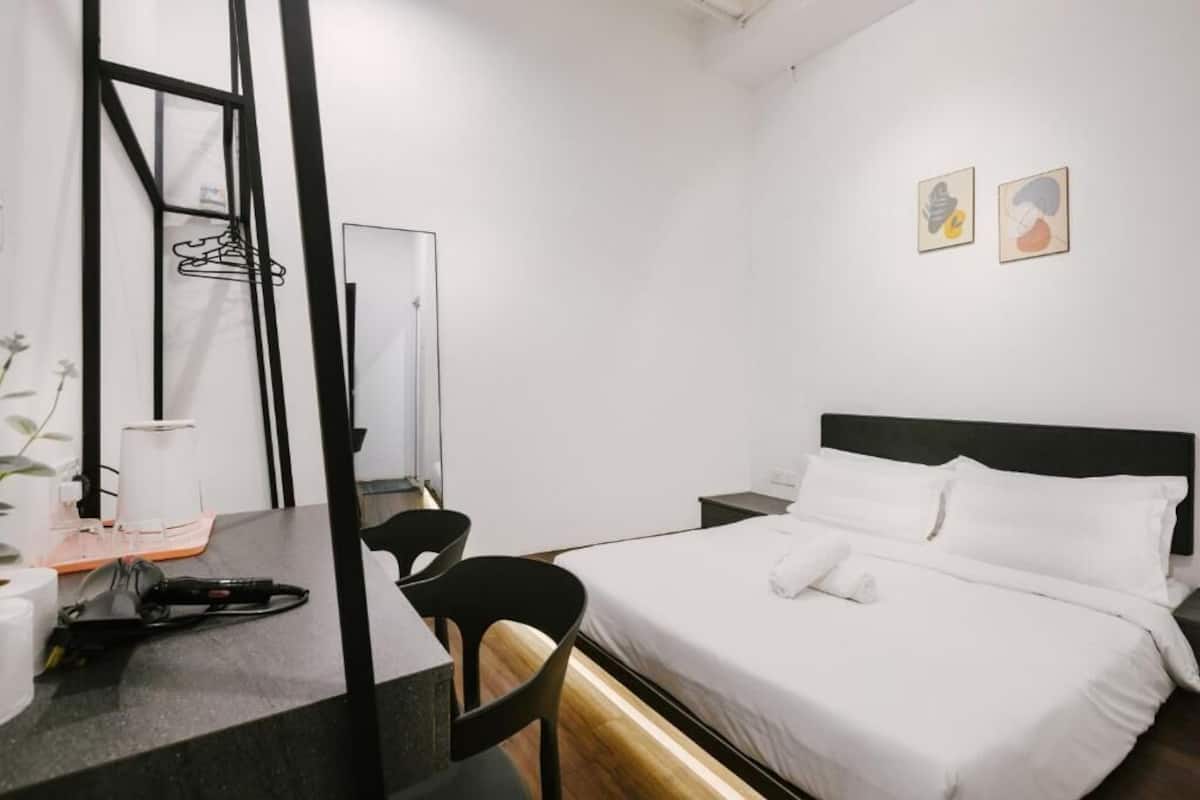 Une chambre d’hôtel comprenant un lit, un bureau, une chaise, un miroir et deux œuvres d’art murales.