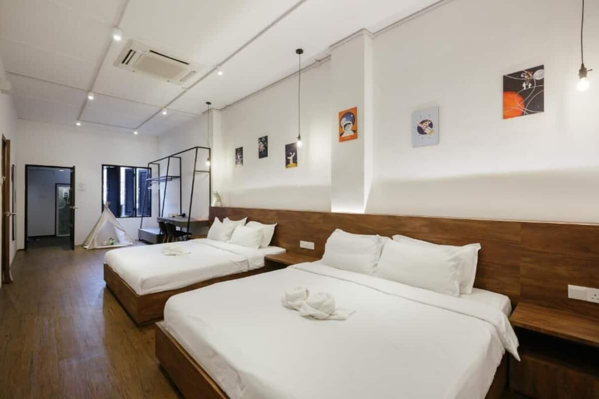 Une chambre d’hôtel avec deux lits, une tête de lit en bois, du linge de lit blanc et des œuvres d’art accrochées aux murs.
