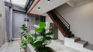 A modern interior with a concrete staircase, a small indoor garden, and a door leading to a room. - Kangsar Inn 73 (George Town)
