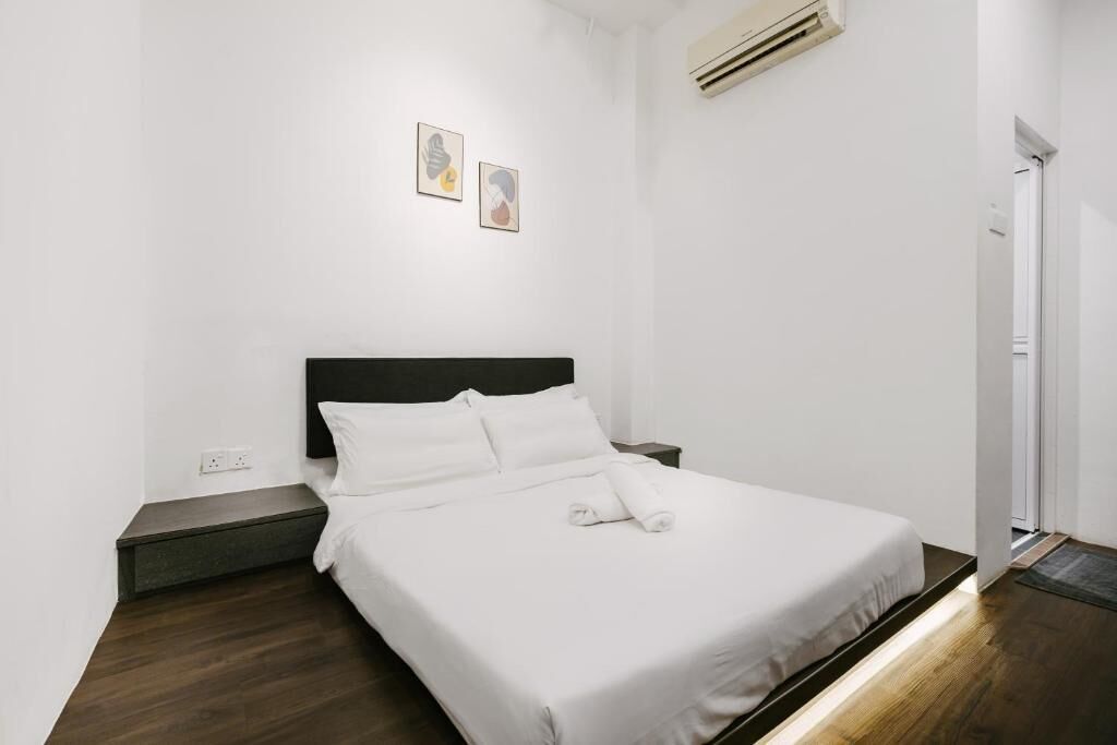 A neatly made bed with white linens, a dark headboard, and a small bedside table.