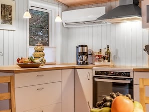 A kitchen with white cabinets, a coffee maker, a stove, and a window with a view of trees. - "Peadda" - 300m from the sea by Interhome (Blokhus)