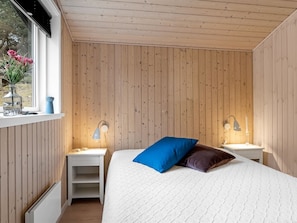 A bedroom with a bed, two bedside tables, a window, and a radiator. - "Peadda" - 300m from the sea by Interhome (Blokhus)