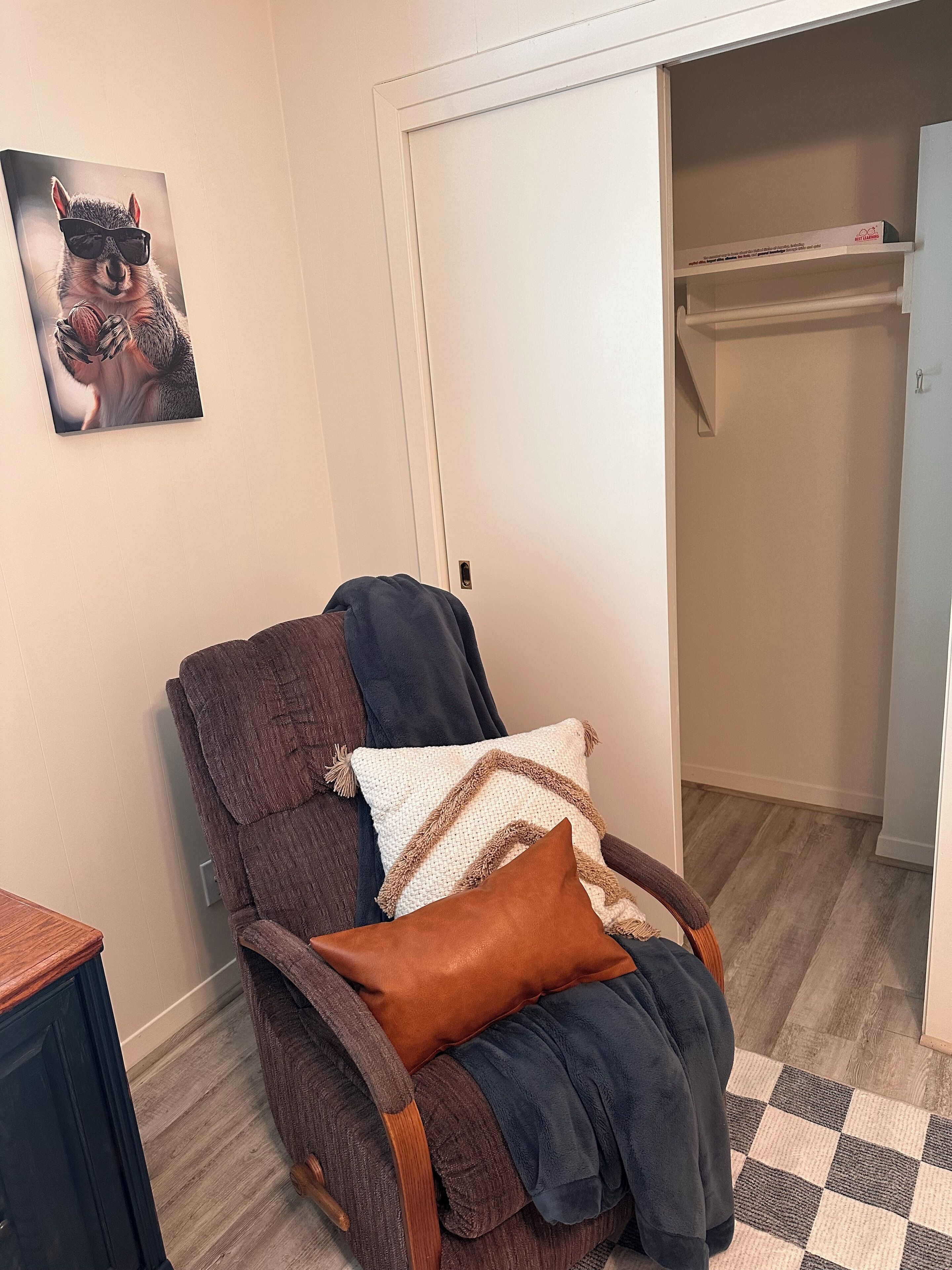 Une pièce avec un fauteuil inclinable marron, une porte blanche et un tapis à carreaux.