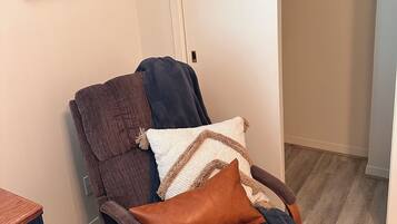 Une pièce avec un fauteuil inclinable marron, une porte blanche et un tapis à carreaux.