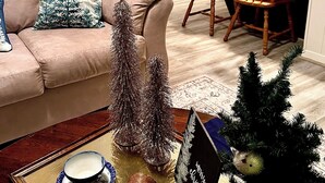 Un salon avec un canapé, une table basse agrémentée d’un objet décoratif et un petit sapin de Noël.
