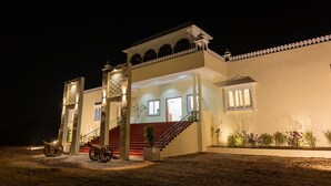 A two-story building with a staircase leading to the upper level, a balcony with railings, and a small porch area. - Vardhan Resorts (Nawalgarh)