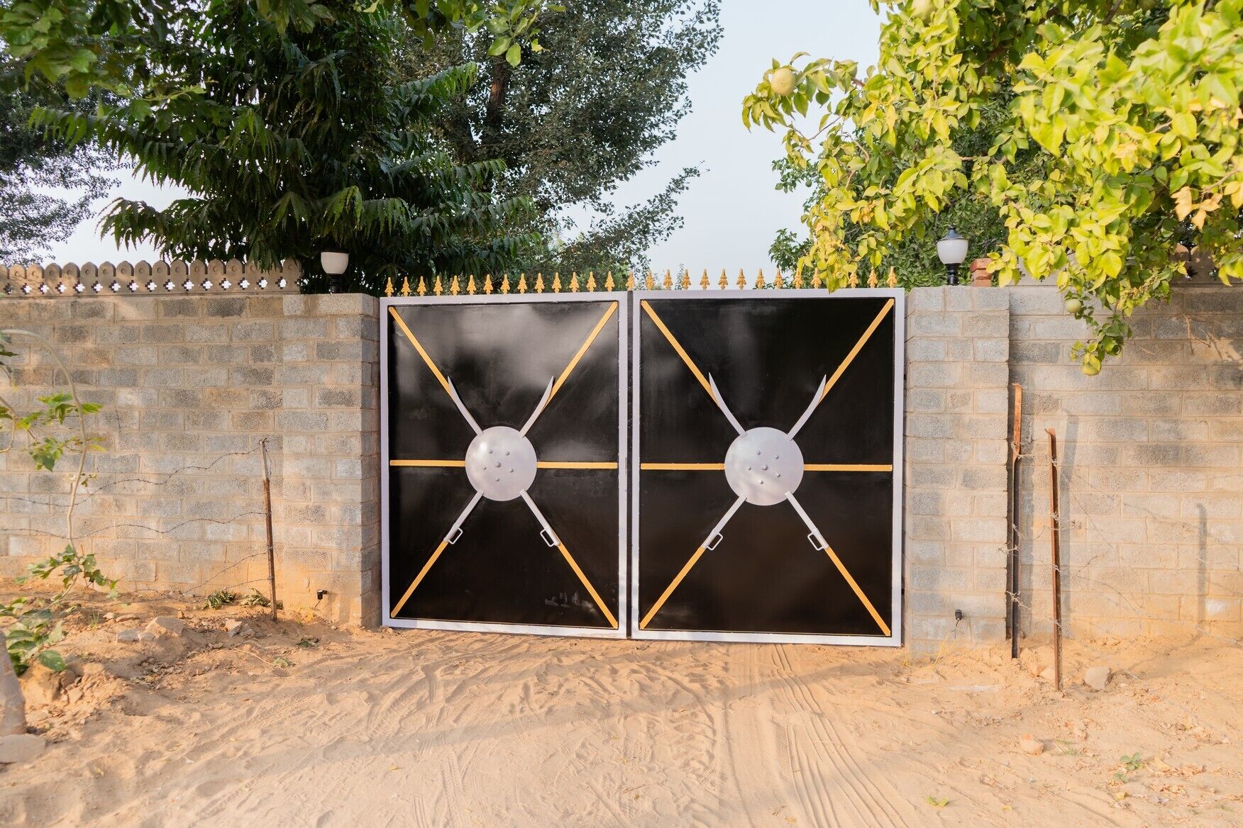 A gated entrance with a metal gate featuring a geometric design and a central circular element.