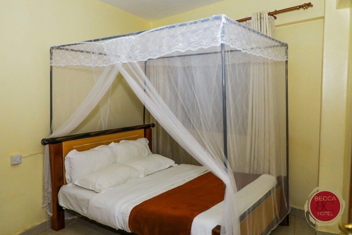 A single bed with a wooden frame and white bedding, covered by a white canopy with lace trim.