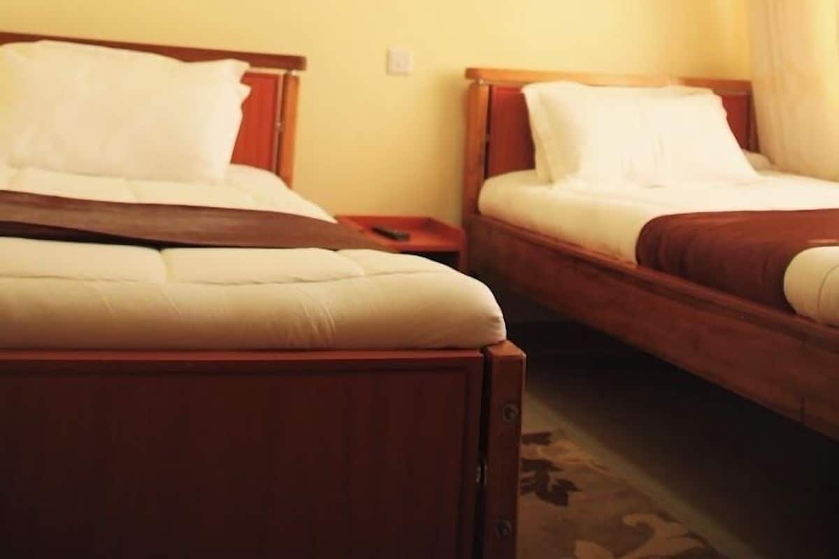A hotel room with two beds, wooden headboards, and a ceiling light fixture.