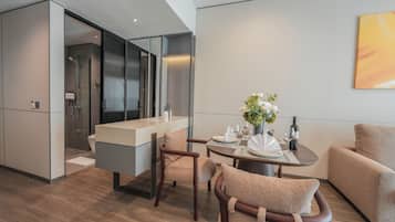 A modern hotel room with a dining area, a sofa, and a large window.