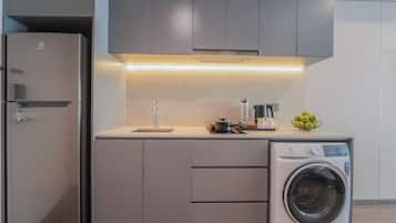 Cozinha compacta com máquina de lavar embutida, pia e bancada com uma tigela de maçãs.