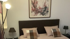 Een hotelkamer met een groot bed, twee nachtkastjes met lampen, een wanddecoratie en een vloerlamp.