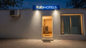 Ein Gebäude mit einem Schild, auf dem 'fabHOTELS' steht, und einem offenen Eingang, der in den Innenbereich führt.