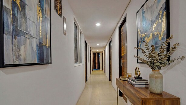 A hallway with a wooden console table, framed artwork, and a vase with foliage. - Fabhotel Silver Key I (New Delhi)