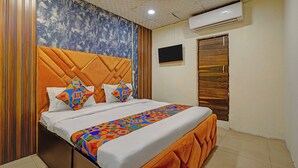A bedroom with a bed, a wooden headboard, a colorful bedspread, and an air conditioning unit. - Fabhotel Silver Key I (New Delhi)