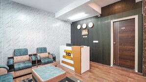 Een hotel lobby met een receptiebalie, een zithoek en een houten deur.