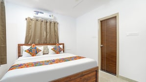 Een slaapkamer met een bed, gordijnen, een houten deur en een plafondventilator.