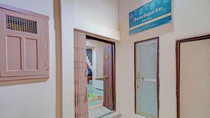 Ein Korridor mit einem Schild für das Shree Gopal Inn, einer Treppe und einer Tür mit einem Metallgitter.