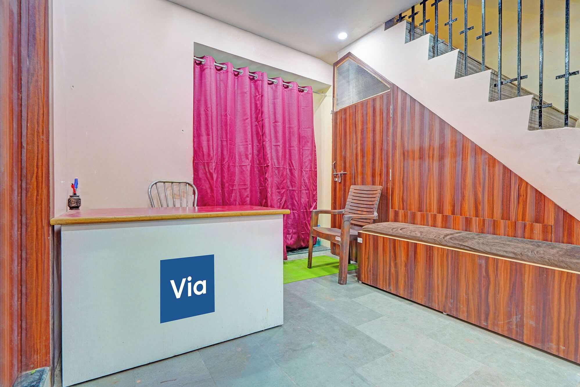 A reception desk with a 'Via' logo, a staircase, and a wooden wall.