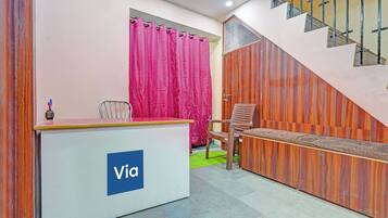 A reception desk with a 'Via' logo, a staircase, and a wooden wall.