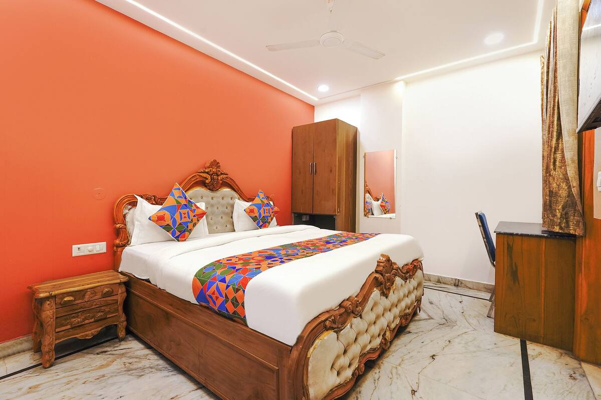 Een slaapkamer met een houten bed, een kledingkast, een spiegel en een klein tafeltje.