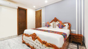 Een slaapkamer met een groot bed, een houten garderobe en een klein nachtkastje.