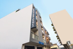 Een hotel genaamd 'Hotel Via' met een modern architectonisch ontwerp, meerdere verdiepingen en balkons.