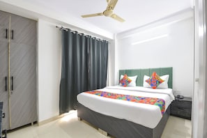 Une chambre d’hôtel équipée d’un lit, d’une table de chevet, d’un téléphone, d’un ventilateur de plafond et d’une armoire.