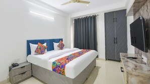 A hotel room with a bed, a desk, a wardrobe, and a ceiling fan. - Via Lochav Residency (New Delhi)