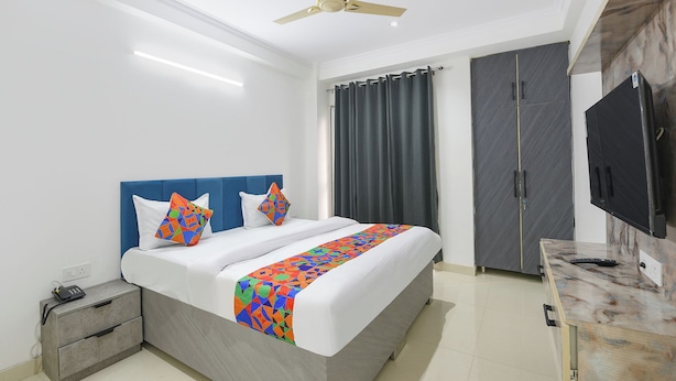 Habitación de hotel con cama, escritorio, armario y ventilador de techo.