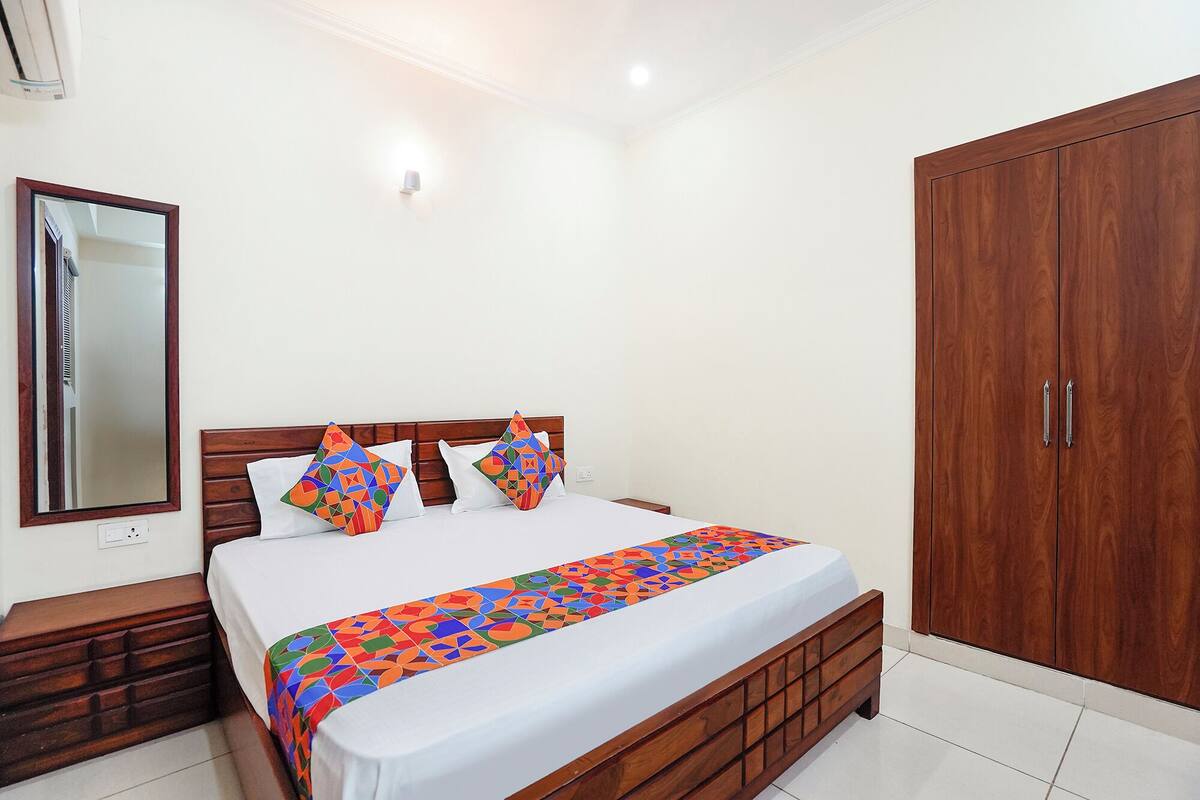 Un dormitorio con cama de madera, mesita de noche, espejo, armario y lámpara de pared.