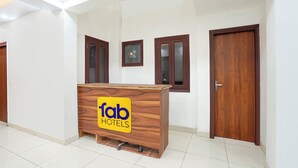 Een receptiebalie met een bordje 'fab hotels' in een hal met witte muren en houten deuren.