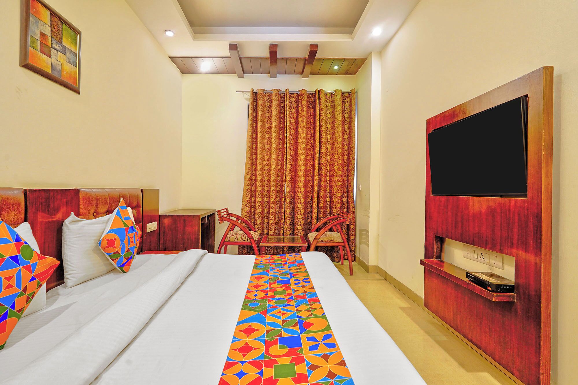 A hotel room with a bed, a TV, a desk, and a chair.