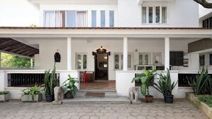 Une maison à deux étages dotée d’un porche couvert, de plantes en pot et d’un hall d’entrée carrelé.