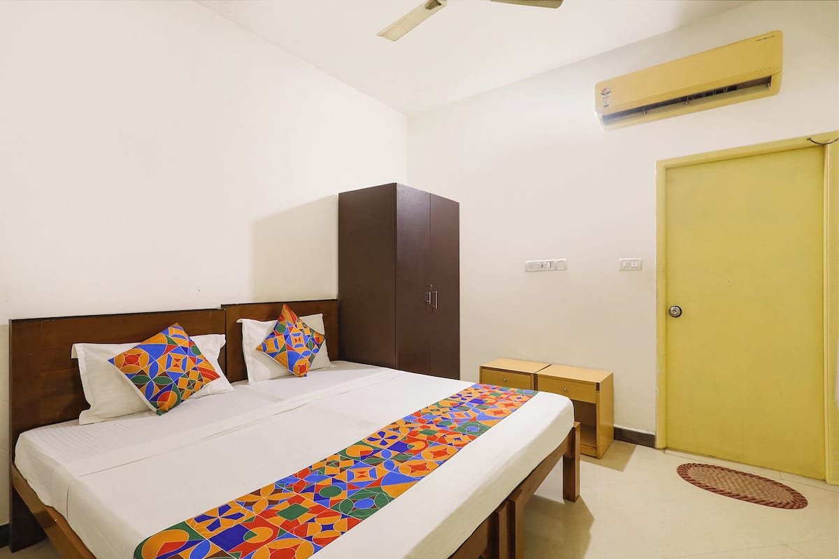 Une chambre d’hôtel comprenant un lit, une armoire, une table de chevet, un appareil de climatisation et une porte.