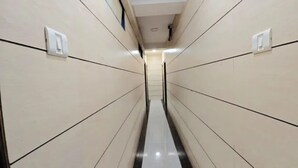 A narrow, tiled hallway with a central walkway and walls on either side. - Fabhotel Kamal (Mumbai)