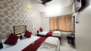 A hotel room with two beds, a TV mounted on the wall, and a window with curtains. - Fabhotel Kamal (Mumbai)