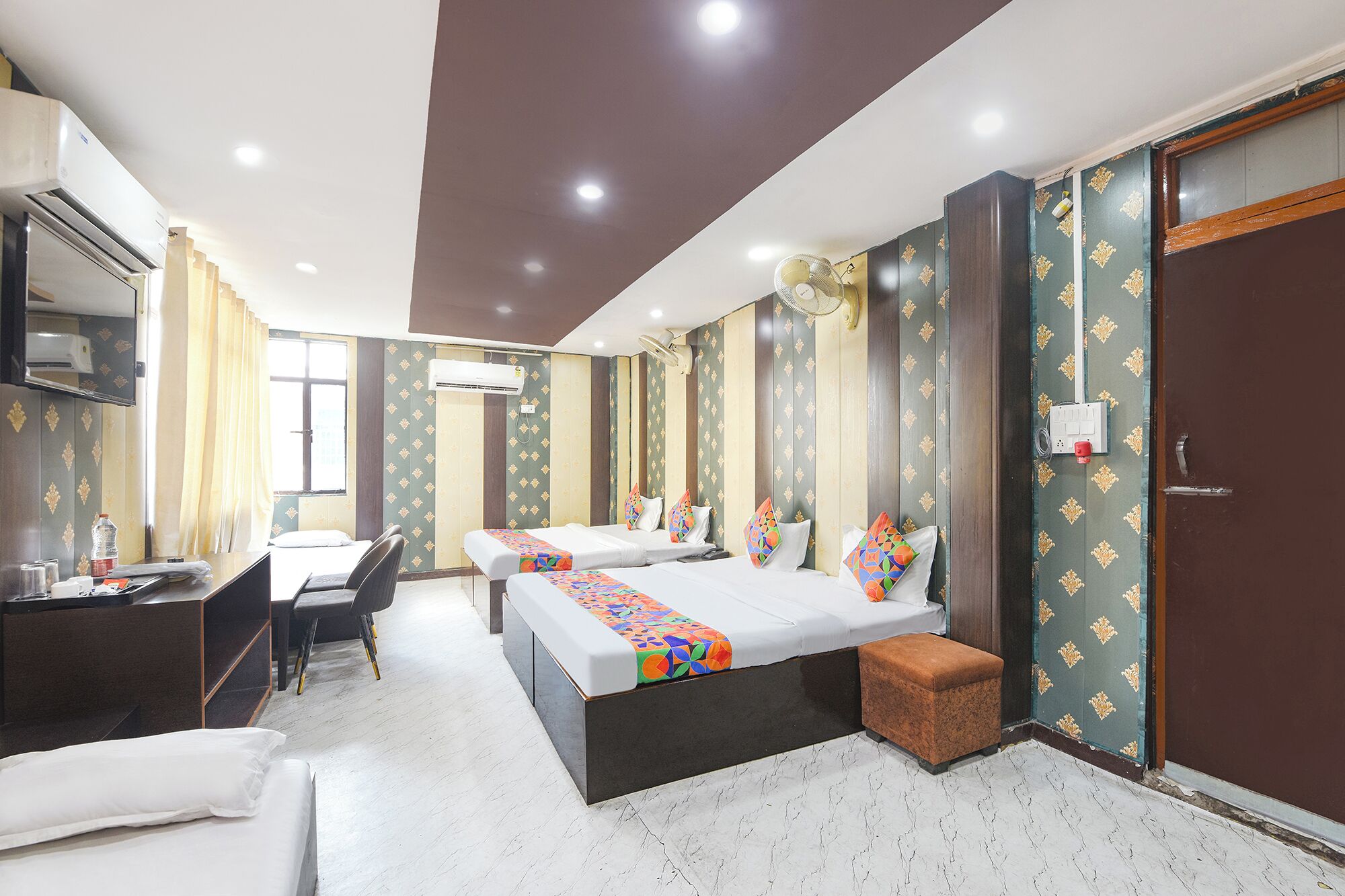 A hotel room with two beds, a desk, and a chair.